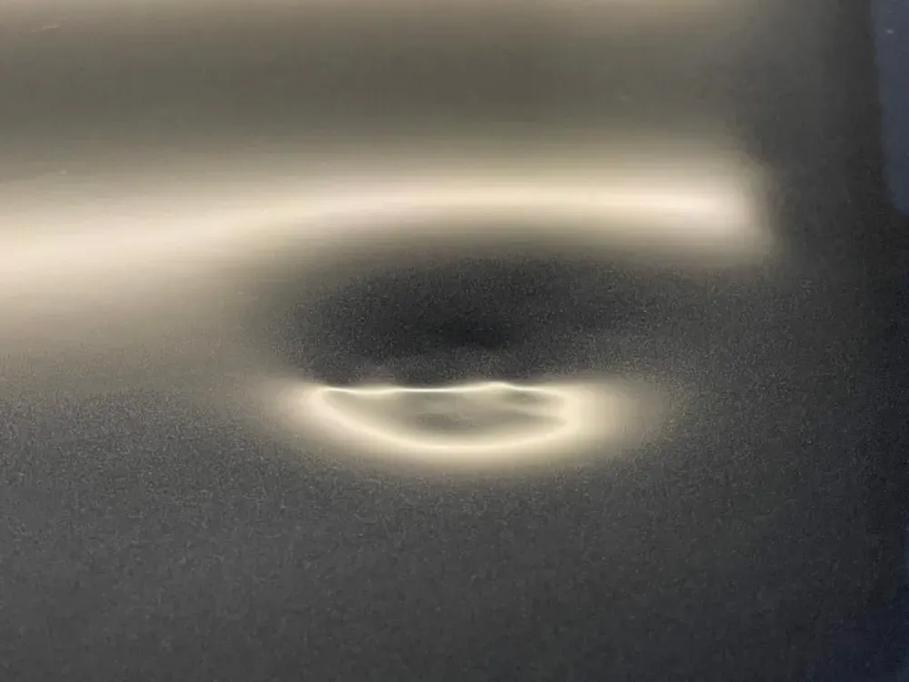 Paintless dent repair light reflecting across a dent in a silver panel